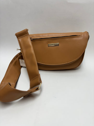 A stylish tan colored faux leather crossbody bag with a wide adjustable strap and gold nameplate on a clean white background.