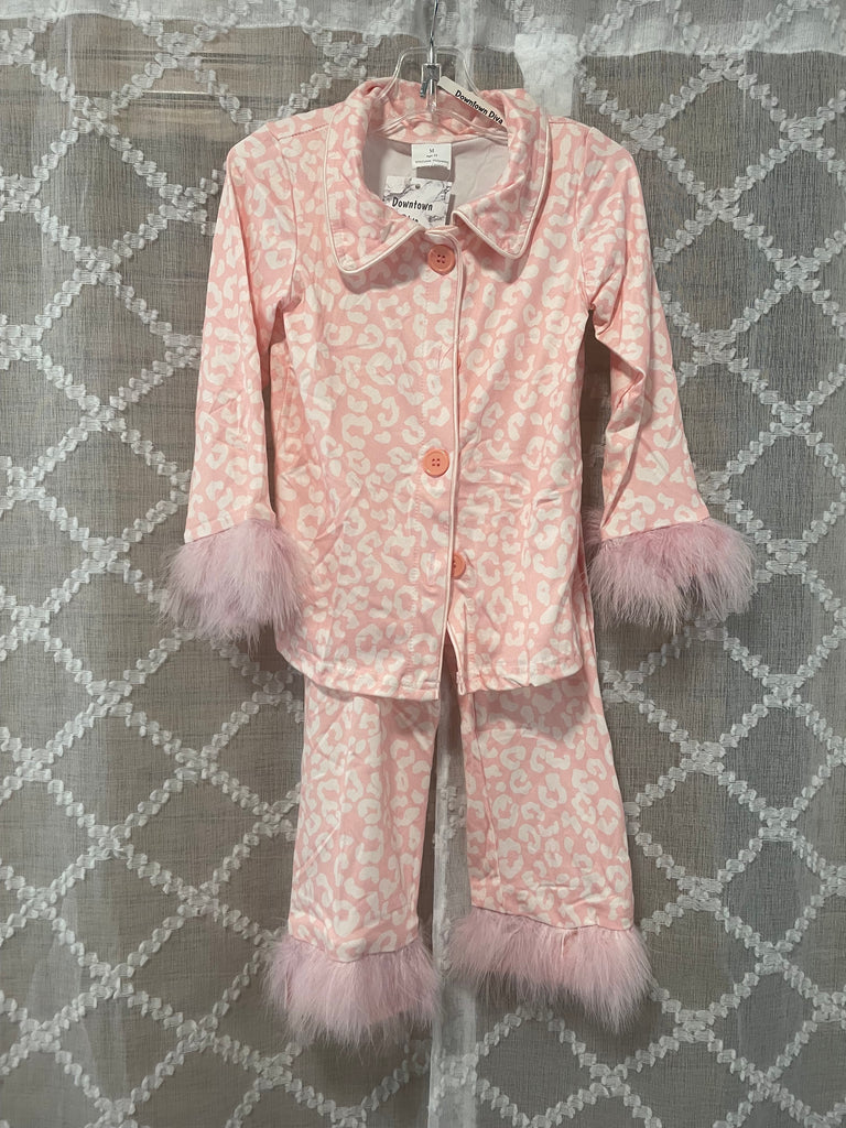 Pink girls' leopard print pajama set with faux fur trim on sleeves and pants, hanging on a hanger in front of a neutral patterned background.