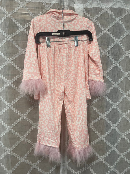 Pink girls' leopard print pajama set with faux fur trim on sleeves and pants, hanging on a hanger in front of a neutral patterned background.