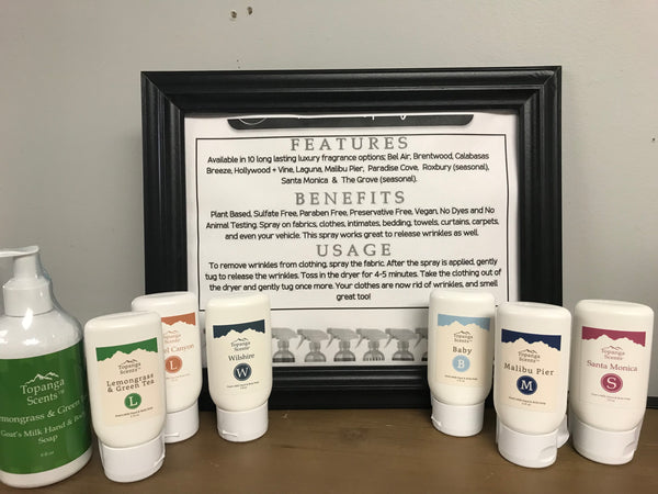 Display of Topanga Scents Goat’s Milk Hand & Body Soaps in various California-inspired scents next to a framed sign detailing features, benefits, and usage instructions