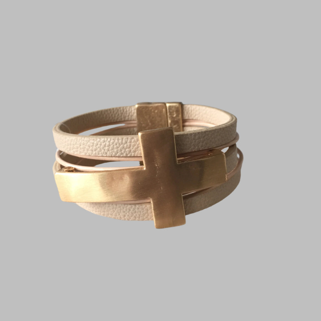 Bracelet. Layered wrap bracelet with tan leather like strands featuring a gold sideways cross and a gold clasp.