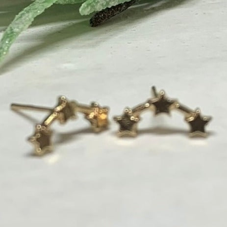 Gold stud pierced earrings featuring 3 gold stars in a simi-circular line.