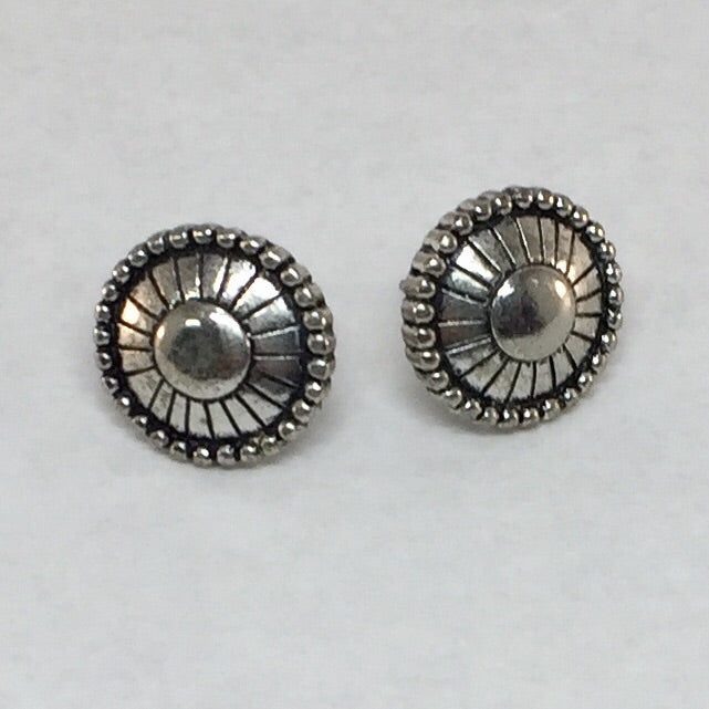 Pierced silver stud earrings: Silver round featuring a circle in the middle and rectangles around leading out to small oblong shapes outlining the earrings.