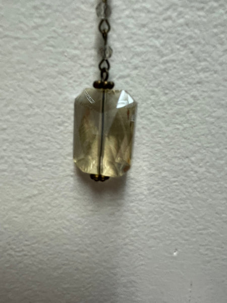 Necklace with a clear crystal pendant on a light gray background