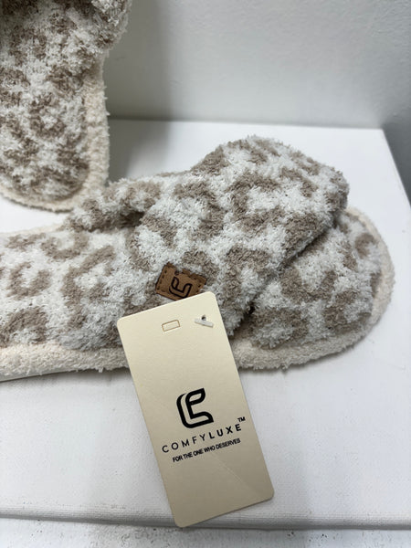 Soft beige and cream leopard print cross band slippers made from plush fabric, displayed on a white background.