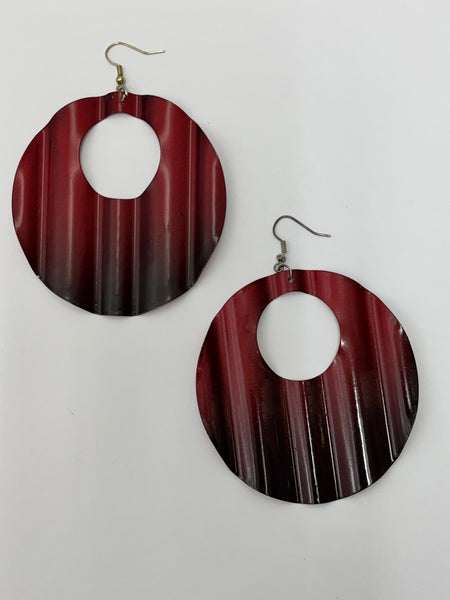 A pair of large circular earrings with an open center, featuring a rippled ombre pattern in shades of black and red