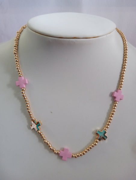 A gold beaded necklace with pink and gold cross charms