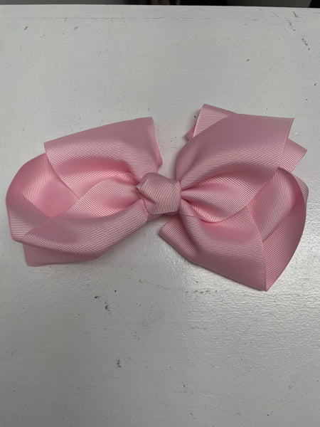 Big baby pink bow on white table.