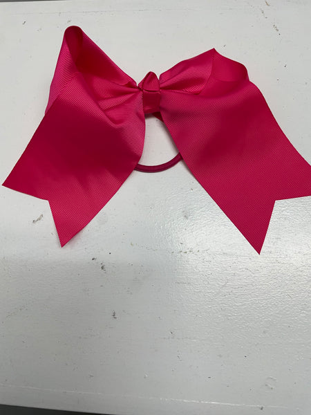 Big hot pink hair tie bow on white table.