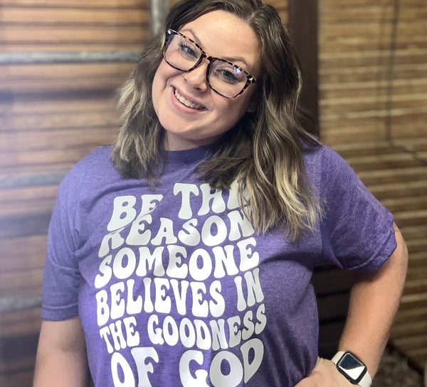 Purple shirt with white lettering quoting "Be the reason someone believes in the goodness of god." 