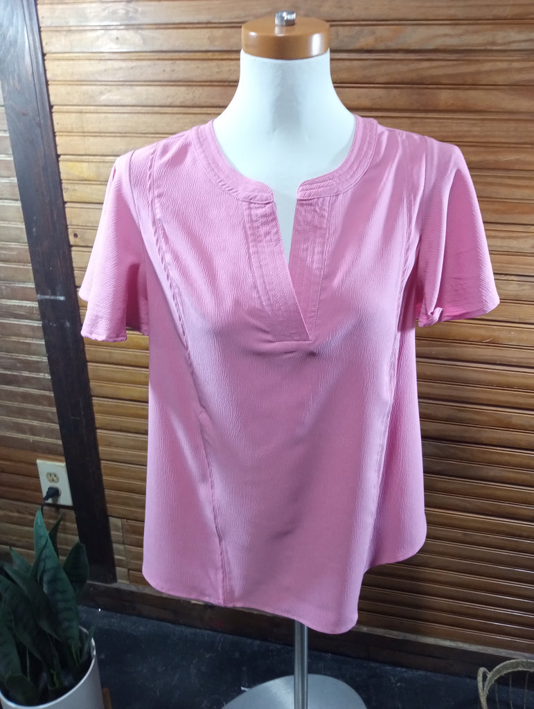 A pink short-sleeve top with a split neckline and button-like center detail
