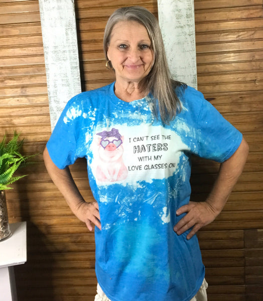 Sublimated blue t-shirt that says "I can't see the haters with my love glasses on" with a pig with heart shaped sunglasses 