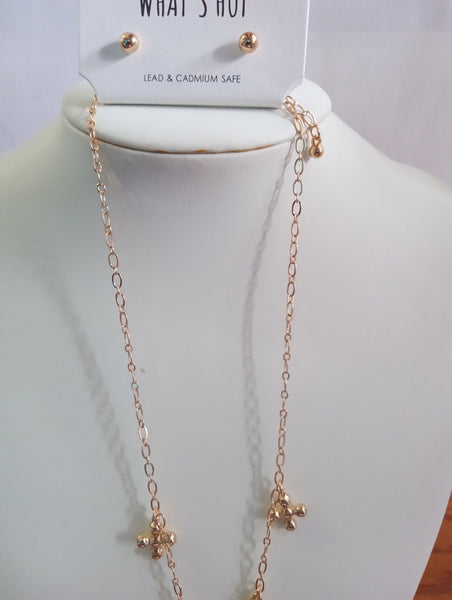 A rose gold chain necklace with small cross charms , with a matching pair of gold stud earrings on a display card at the top.
