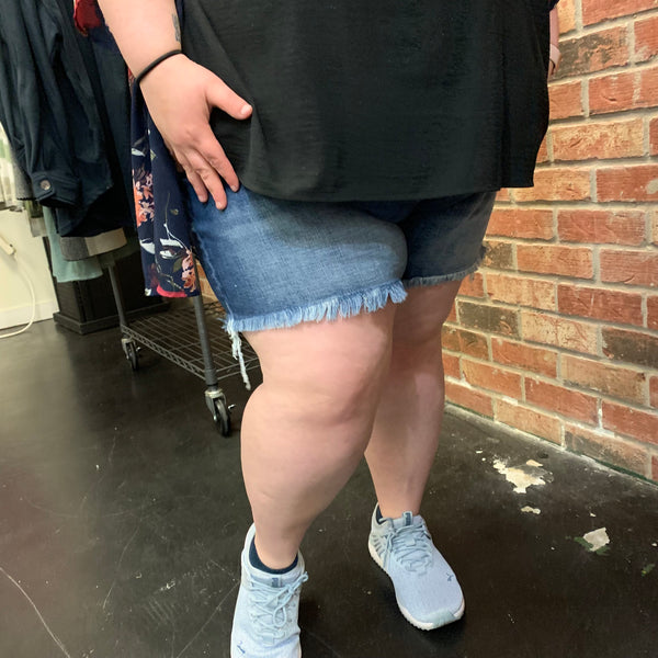 Denim blue jean shorts with fringe around the legs