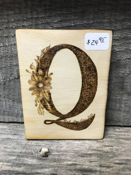 Wood burned Q with flower on Q.