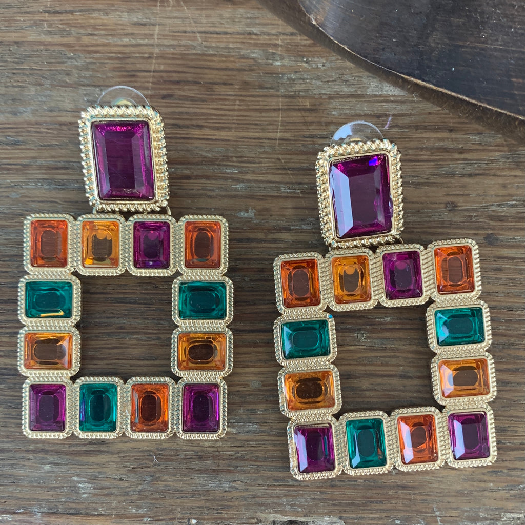 Pierced earrings with a purple rectangle piece outlined in gold at the top and a large hollow square of color rectangle piece (orange/yellow/purple/blue) outlined in gold at the bottom. 