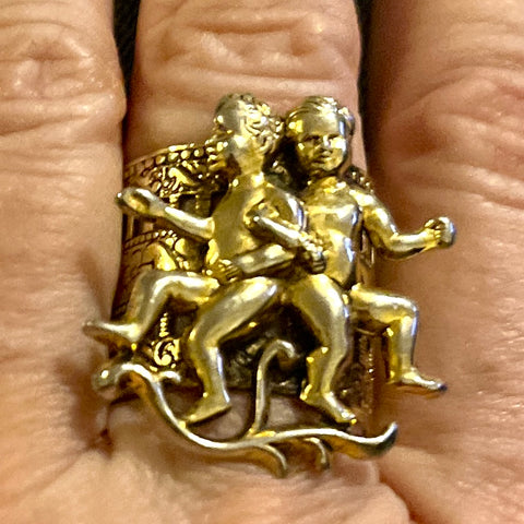 Adjustable gold colored ring with a set of cute little cherubs at the focal point the band is wide and detailed.
