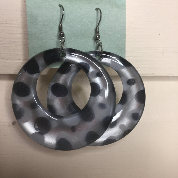 Pierced silver hook earrings: Hoop earrings with silver background and black polka dots.