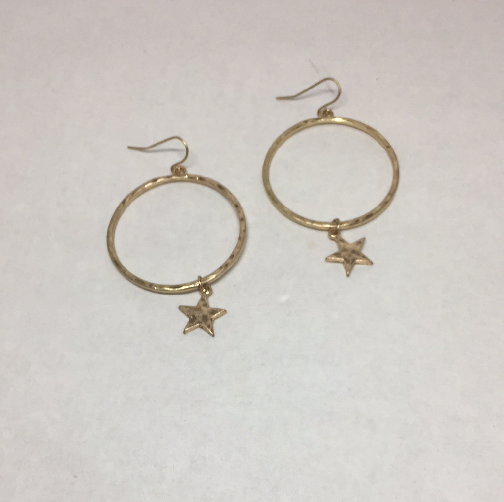 Pierced gold hoop earrings with gold star at bottom of hoop.