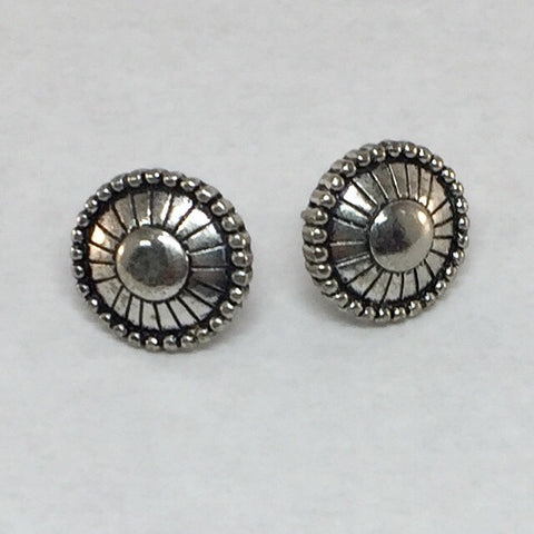 Pierced silver stud earrings: Silver round featuring a circle in the middle and rectangles around leading out to small oblong shapes outlining the earrings. 