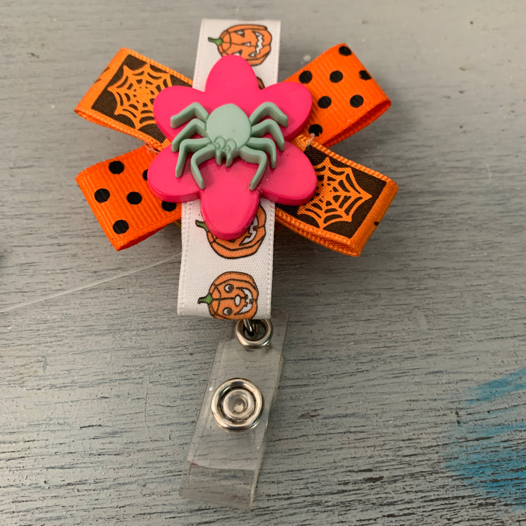 Halloween Decorative Badge Reel with spider on front. Colors: Orange, Black, White, Pink, Green 